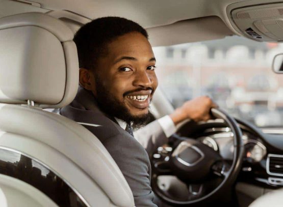 african american man suit smiles looks his shoulder while driving car he appears web